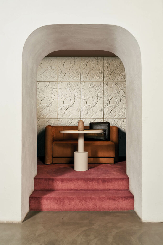 an archway with cream ceramic tiles and blush carpet floor