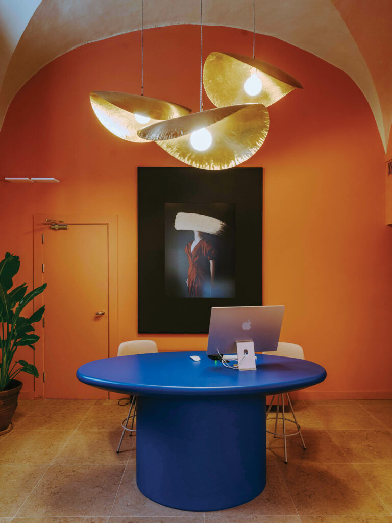 bright lobby with orange walls, wedge pendants and a dark blue standing table