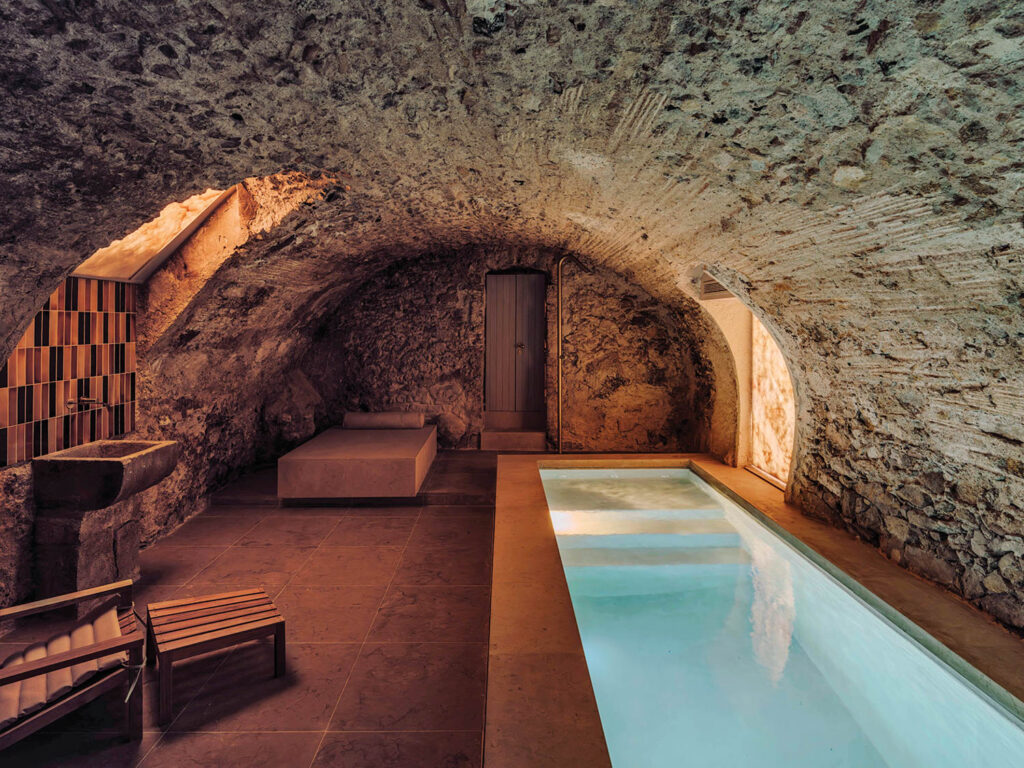 spa room with stone overhead and lit swimming pool