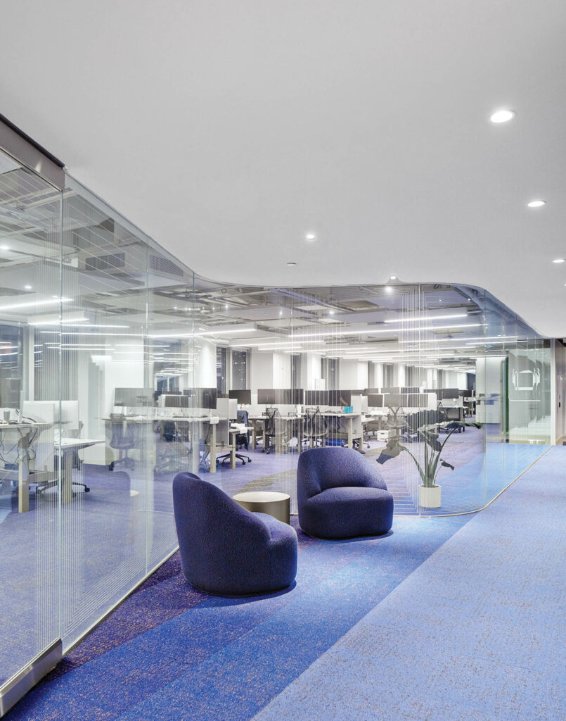 a common area in an office with two blue armchairs