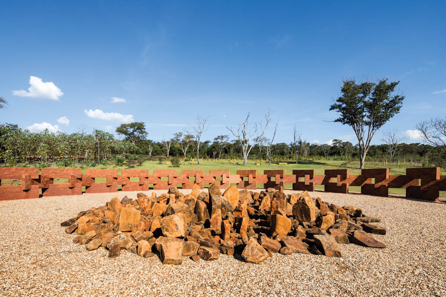 terracotta rock sculpture in the middle with surrounding trees in background