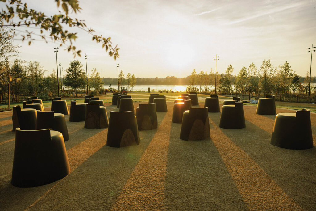 A monument made of rows of sculptural forms on grass at sunset