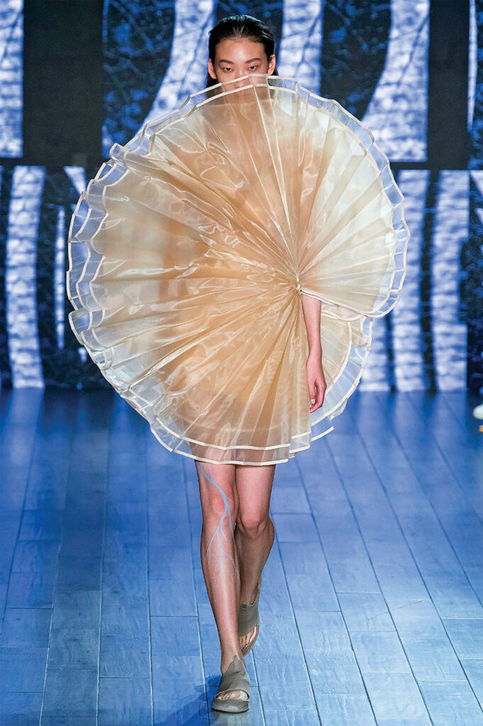 model walking down runway with a gossamer web-like gown