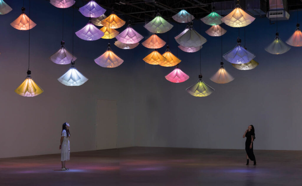dark lit room with multiple colored lanterns hanging from the ceiling
