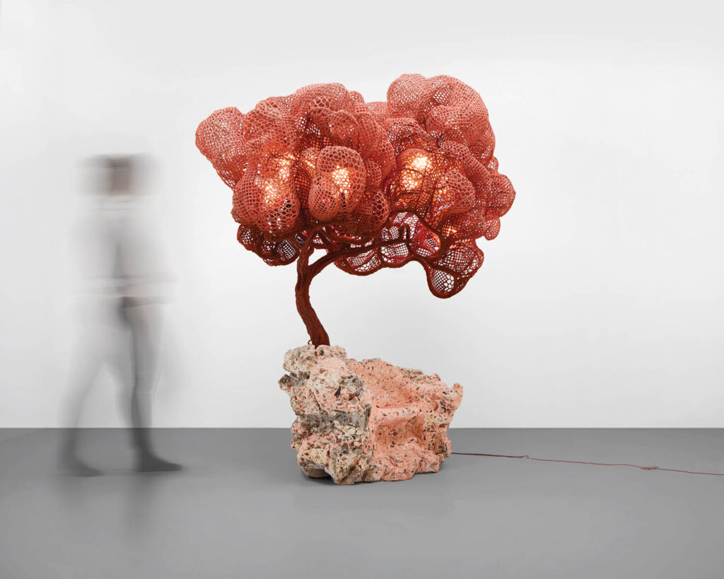 reddish sculpture resembling a tree on a rock