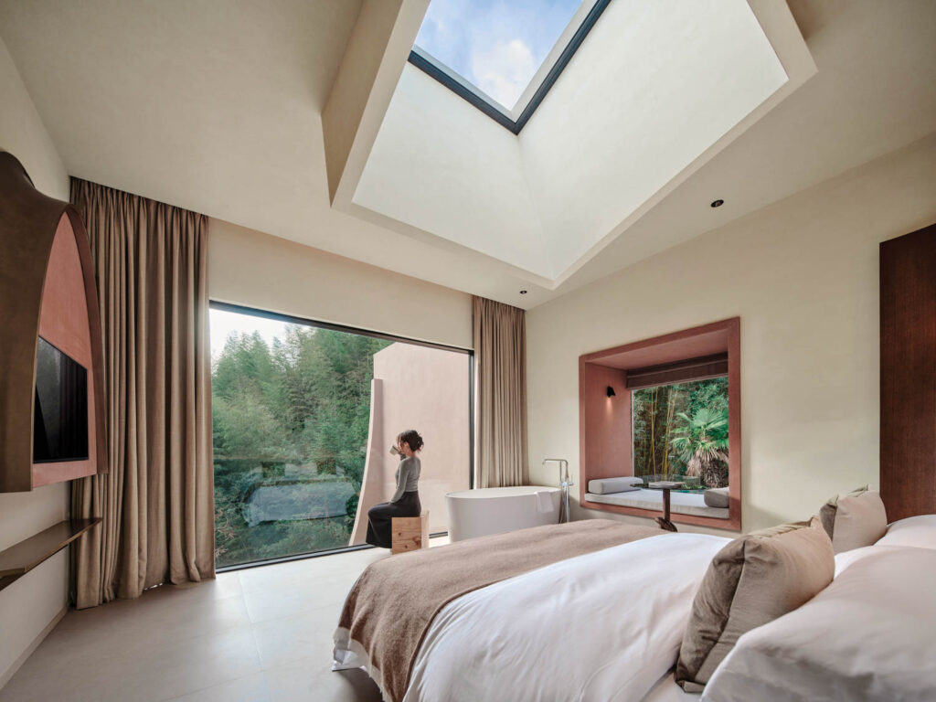 room with high ceiling, brown bed and view to outside scenery